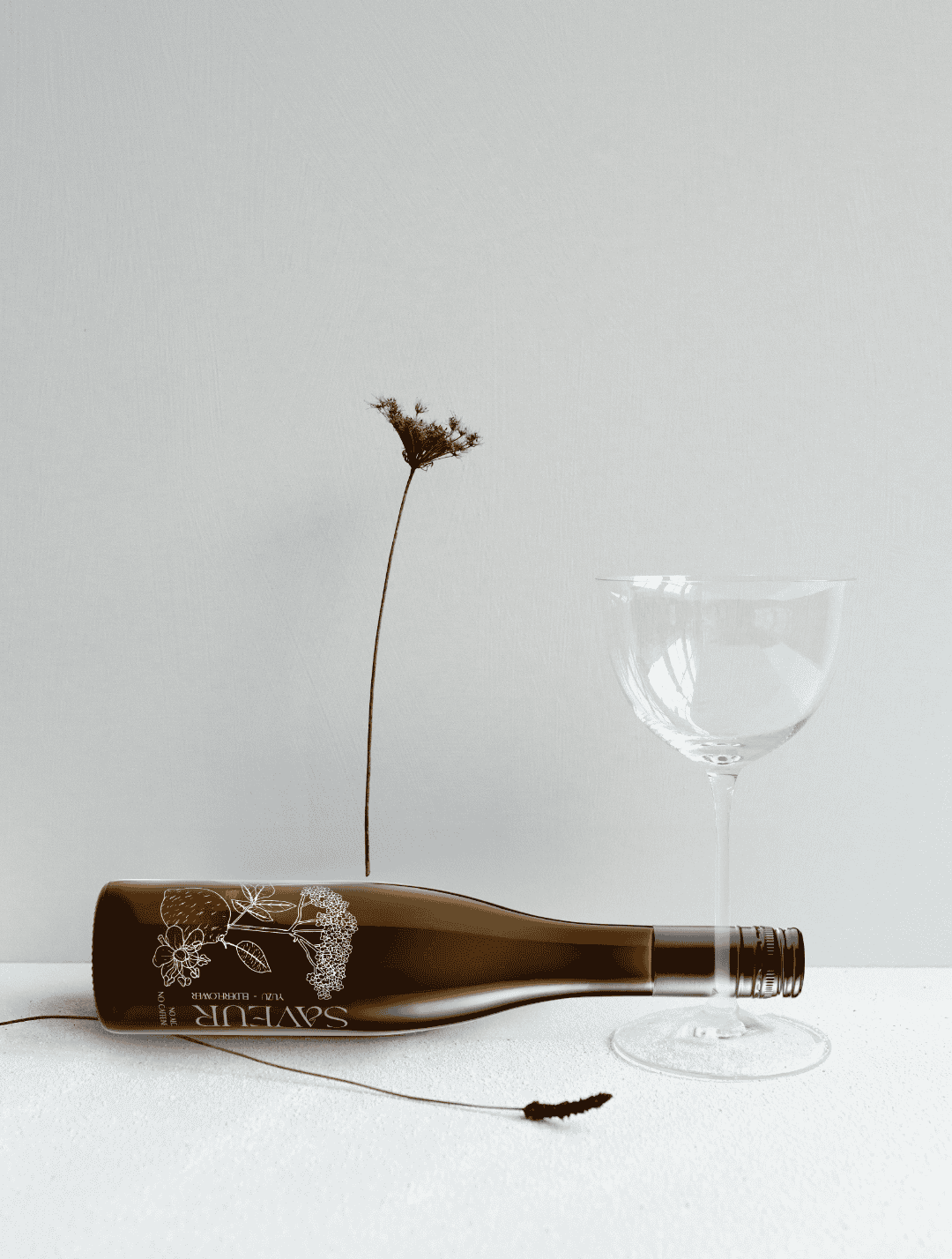Saveur Drinks Weinflasche mit Weinglas und einer Blume auf weißem Untergrund